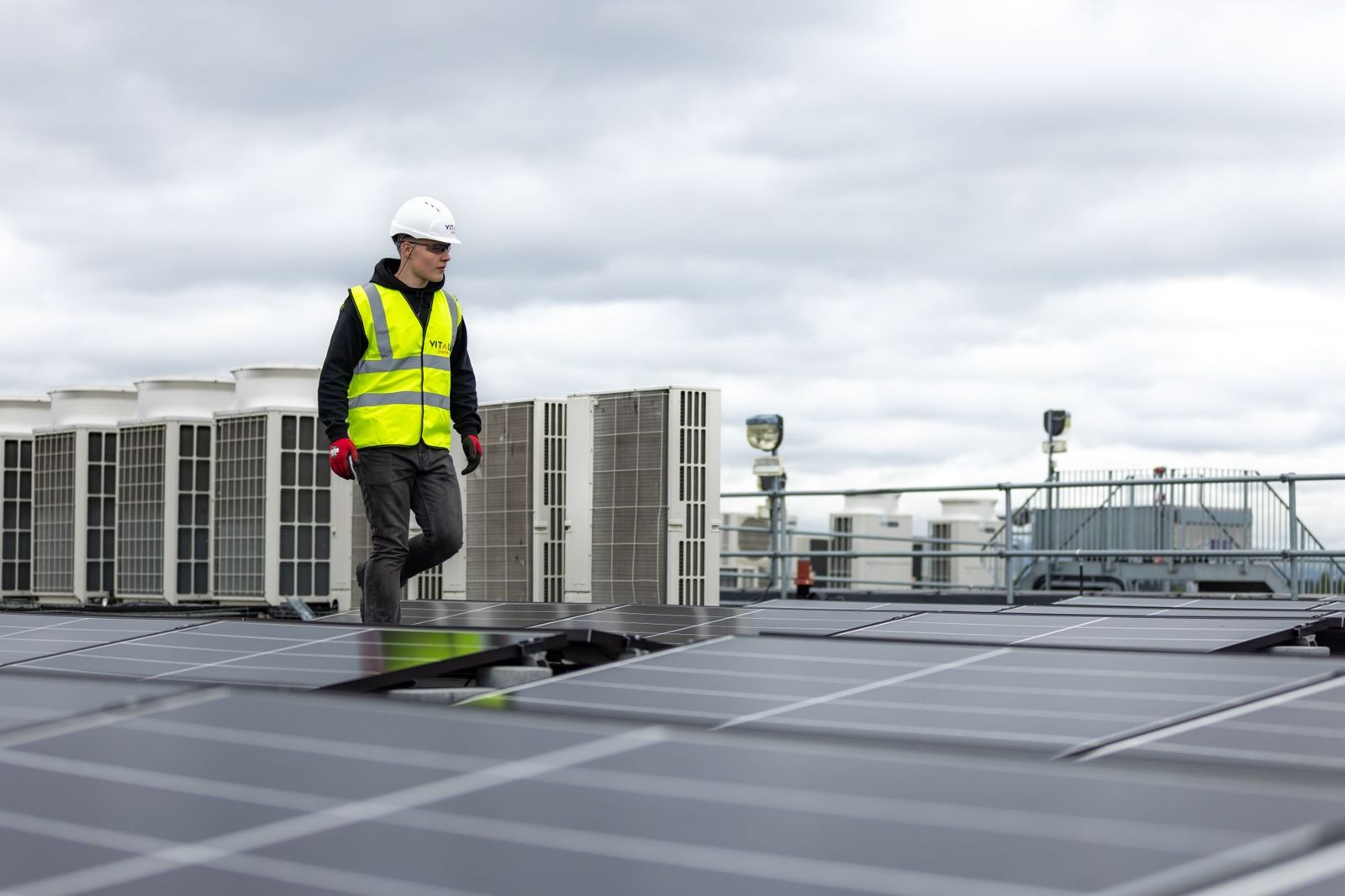 Techniker in Warnweste geht über eine Photovoltaikanlage auf einem Flachdach
